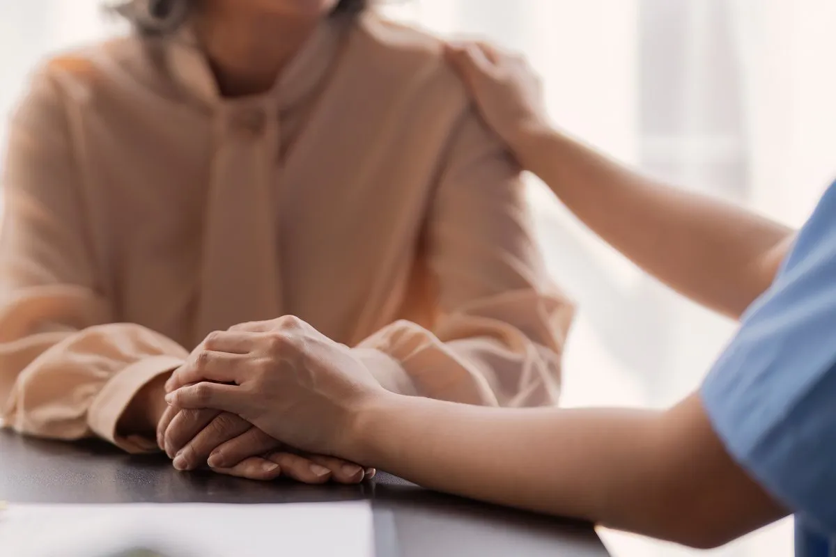 A carer's reassuring hand on a client's shoulder