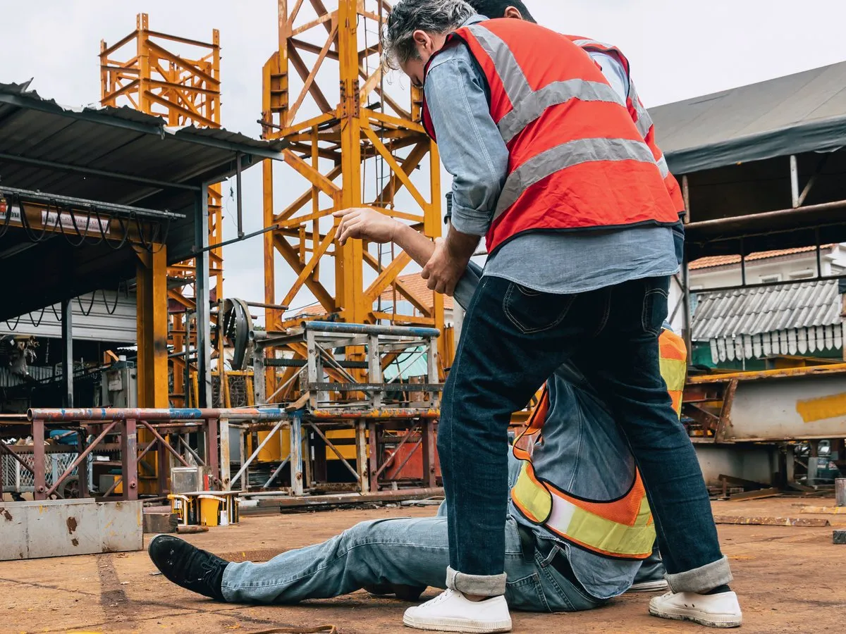 A first aider checking on an injured worker on a construction site