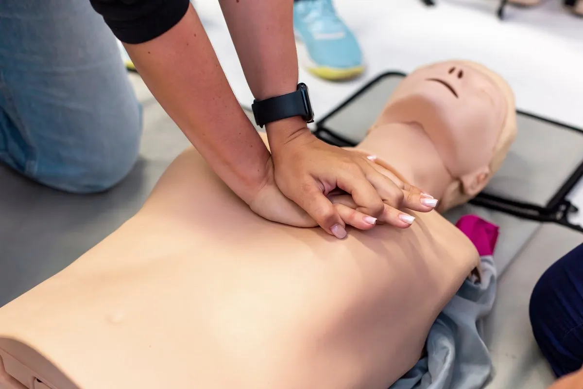 Hands practising CPR on a training manikin